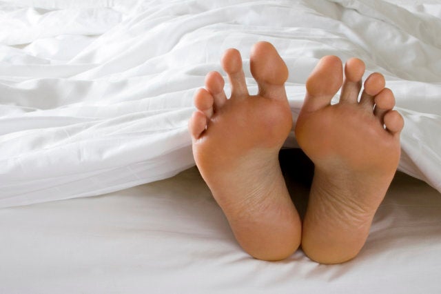 A man's feet poke out of the bottom of a white duvet in bed. Similar images from my portfolio: