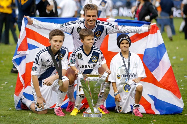 Los Angeles Galaxy's David Beckham, top center, of England, poses with his sons, from left, Brooklyn, Romeo and Cruz after the Galaxy's 3-1 win in the MLS Cup championship soccer match against the Houston Dynamo in Carson, Calif., Saturday, Dec. 1, 2012. (AP Photo/Jae C. Hong)