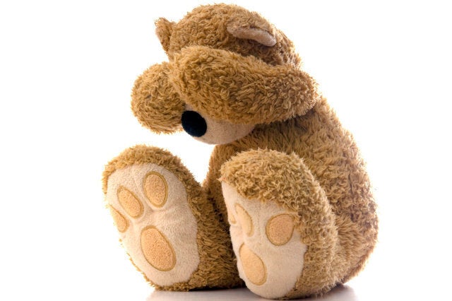 Teddy bear sad and crying into hands.