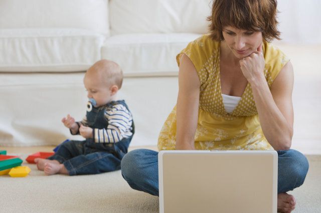 Mother using laptop while baby plays