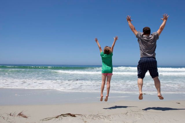 Father and daughter jumping at the beach