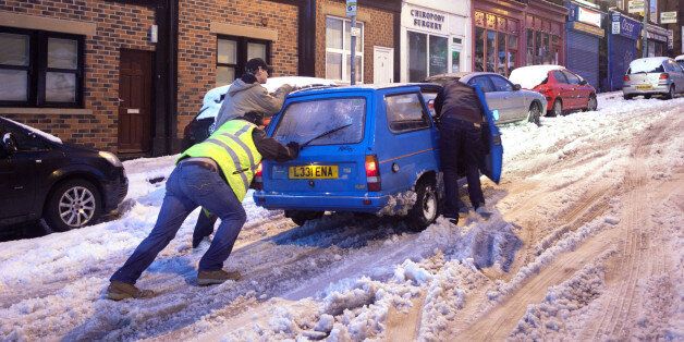 People push a car in snowy conditions in the Crookes area of Sheffield after wild and wintry weather swept the UK, with travellers left stranded as heavy snow covered roads and forced two airports to close.