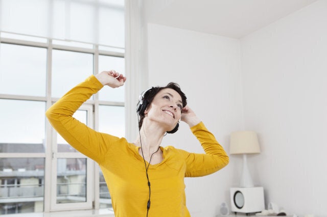 Germany, Bavaria, Munich, Mid adult woman listening music, smiling