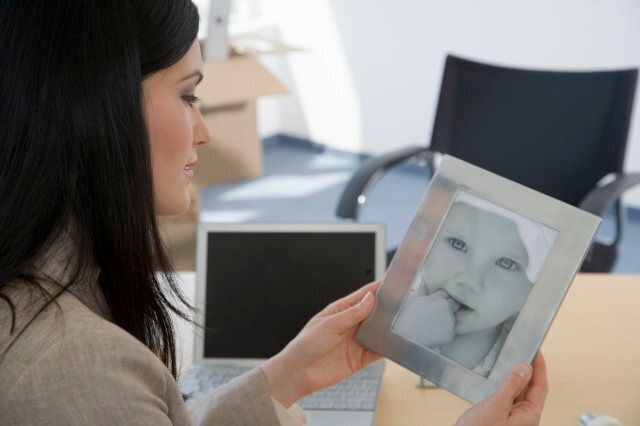 Businesswoman looking at photograph of baby on desk