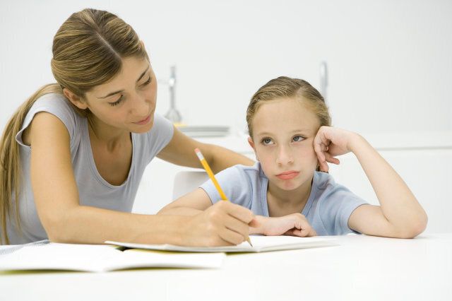Mother helping daughter with homework, girl looking away and sulking