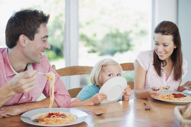 Parents watching daughter licking dinner plate