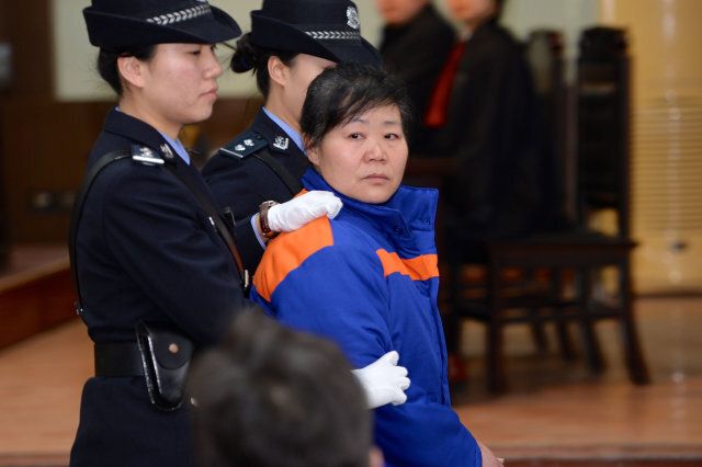 Zhang Shuxia (C), a Chinese former obstetrician, is escorted by two police officers in Weinan Intermediate People's Court in Weinan, north China's Shaanxi province on January 14, 2014. Zhang was given a suspended death sentence on January 14 for abducting newborn babies and selling them to traffickers, in a case that drew widespread outrage. CHINA OUT AFP PHOTO (Photo credit should read STR/AFP/Getty Images)
