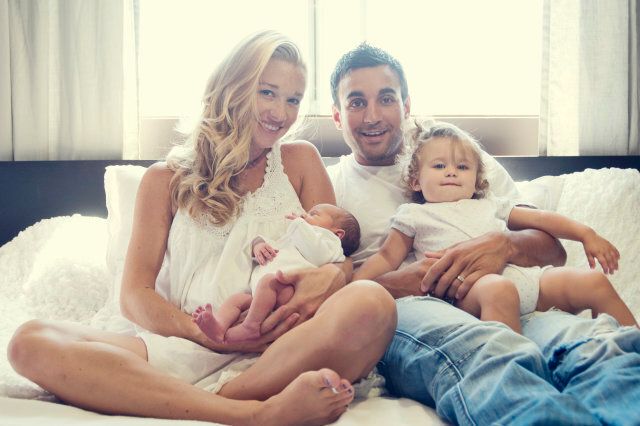 Family in bed holding newborn baby