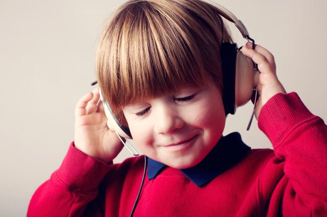 A young boy listens to music on a pair of headphones