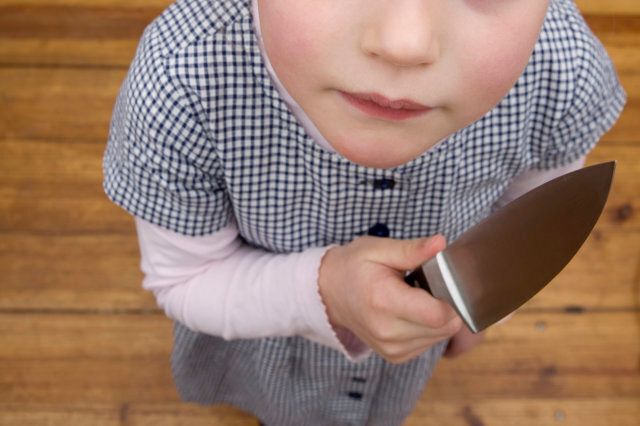 A young girl holding a sharp knife menacingly