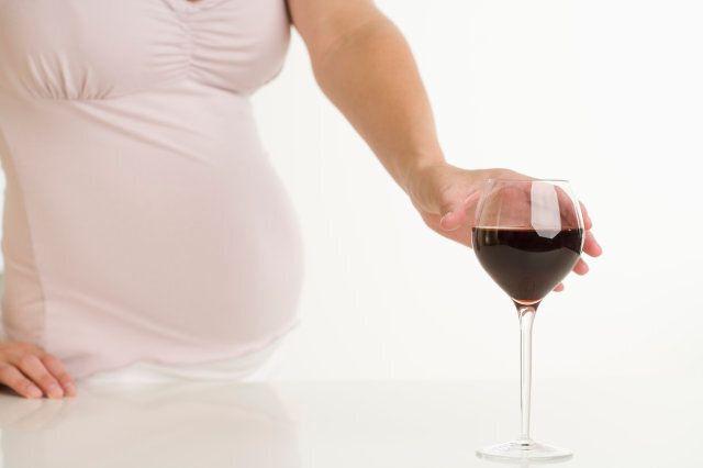 Pregnant Woman Reaching for Glass of Wine