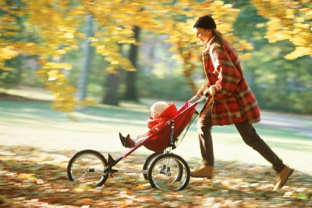 Mother pushing baby (12-15 months) in pushchair (blurred motion)