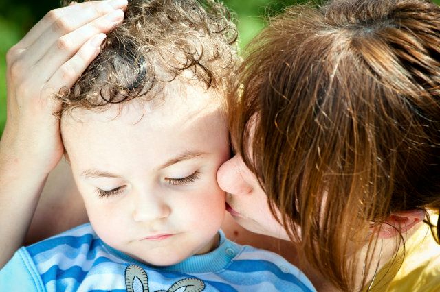 Sad little boy under mother's protection