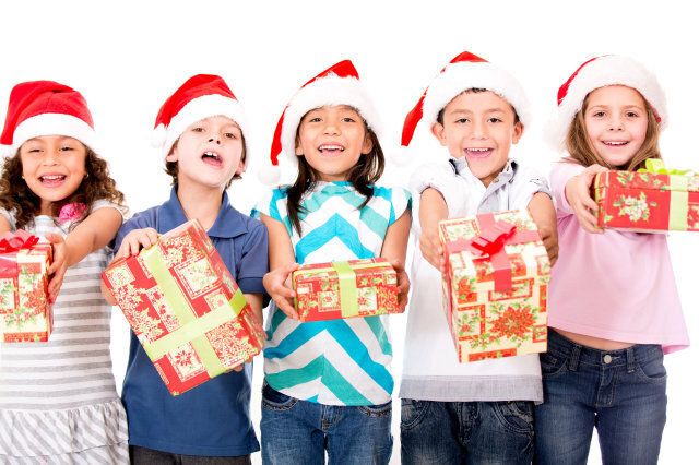 Group of kids holding Christmas presents - isolated over a white background