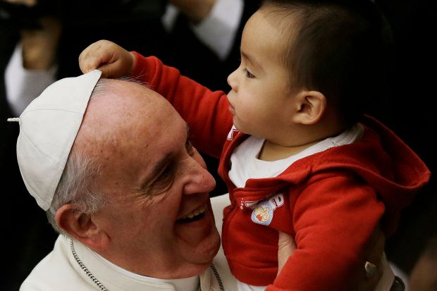 A child takes off Pope Francis' white zucchetto, or skullcap, during a meeting with children and volunteers of the Santa Marta Vatican Institute, at the Vatican, Saturday, Dec. 14, 2013. (AP Photo/Gregorio Borgia)