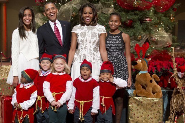 US President Barack Obama, First Lady Michelle Obama and their daughters, Sasha (R) and Malia (L), pose for photographs alongside children dressed as elves, who are or were patients at Children's National Medical Center after they presented donated gifts to the Obamas to give to children at the hospital, as they attend a taping of TNT's Christmas in Washington at the National Building Museum in Washington on December 15, 2013. The annual event, hosted by actor Hugh Jackman, features performances by the Backstreet Boys, Anna Kendrick, Sheryl Crow, Janelle Monae and Pat Monahan, and airs on the TNT television network on December 20. AFP PHOTO / Saul LOEB (Photo credit should read SAUL LOEB/AFP/Getty Images)
