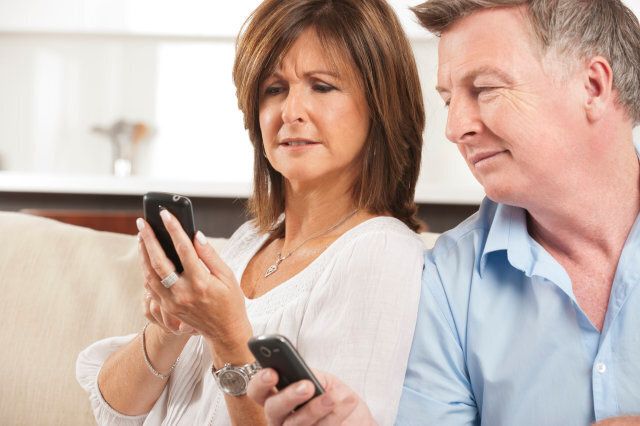 Concerned Mature Couple looking at each others mobile phones