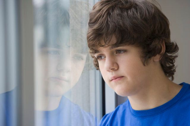Teenaged boy looking out window