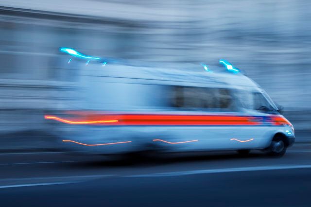 blurred police van driving fast with the flashing emergency lights, blue toned image