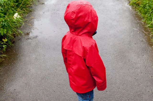 Back view of toddler standing on pathway in red raincoat