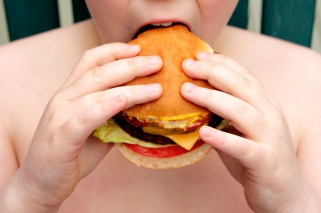 Overweight boy eating cheeseburger