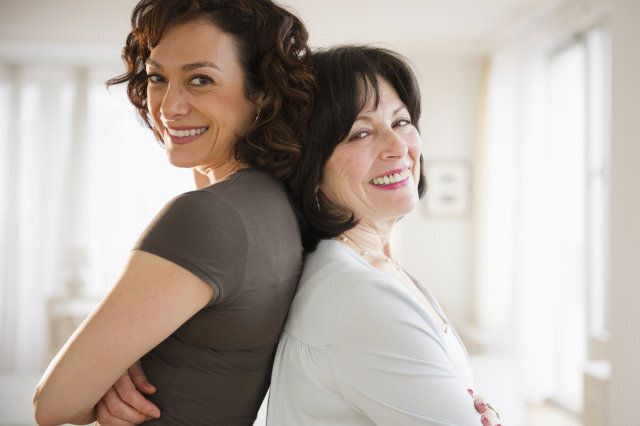 Adult daughter and mother standing back to back