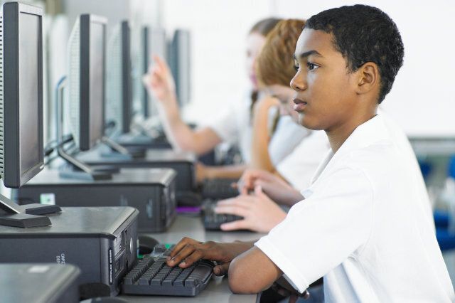 Students (13-15) using computers in class, side view