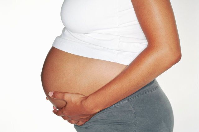 Pregnant woman touching stomach, mid section