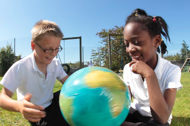 school children looking at globe