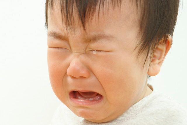 Close-up of a baby boy crying against white background