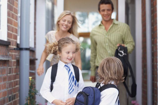 Parents leaving house for school with son and daughter (4-6) smiling