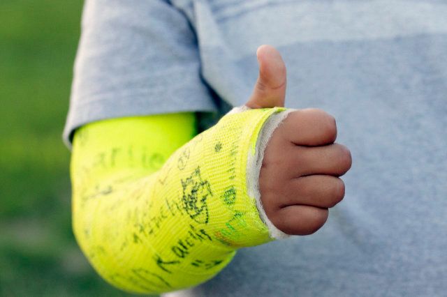 Boy giving thumbs up sign with broken arm in cast