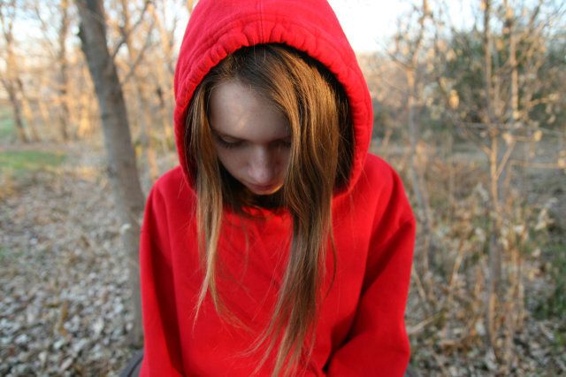 Teenage girl wearing a red hoodie looking down, Brooklyn Park, Minnesota