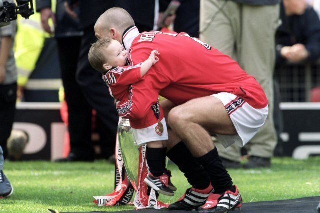 Manchester United's David Beckham gives his son Brooklyn a hug