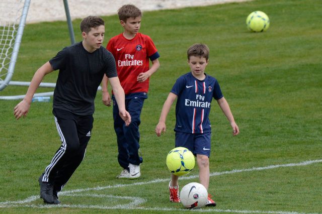 Brooklyn (L), Romeo (C) and Cruz (R), children of Paris Saint-Germain's English midfielder David Beckham, play while their father takes part in a training session on April 19, 2013 at the French L1 football club PSG's training camp in Saint-Germain-en-Laye, near Paris. AFP PHOTO / BERTRAND GUAY (Photo credit should read BERTRAND GUAY/AFP/Getty Images)