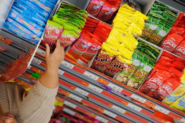 UK supermarket shelves stacked with sweets - a shopper reaches for a packet.