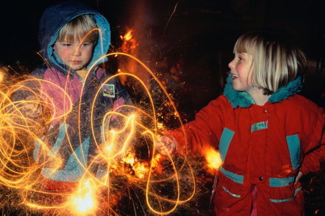 Two children (4-7) playing with sparklers at night