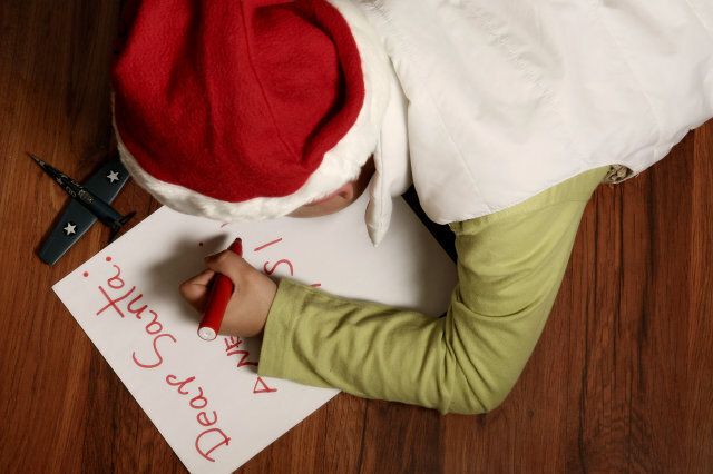 A seven yaers old boy writting SantaA's letter with a toy airplane
