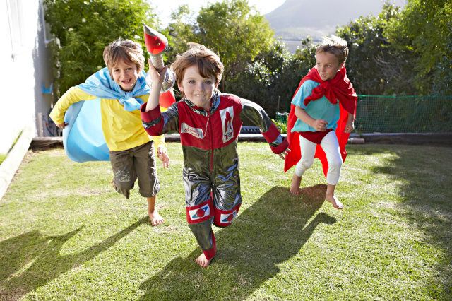 Boys, aged 6-7, pretending to be astronauts and superheroes in a suburban garden