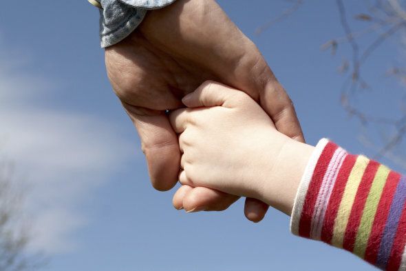Dad holds the hand of his young daughter