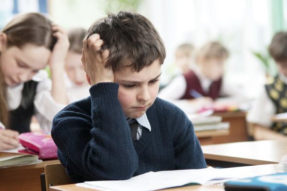 Schoolboy sitting at the classroom and working hardly