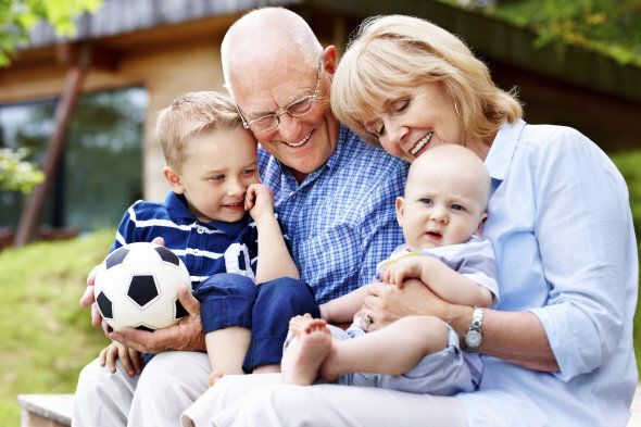 Portrait of happy grandparents with their grandchildren sitting outdoors
