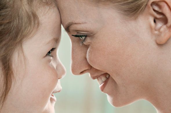 A smiling mother and daughter touching foreheads, close-up