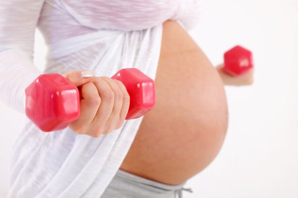 Sporty pregnant woman holding weights.