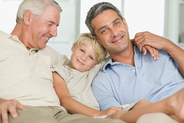 Little boy relaxing on couch with grandfather and father