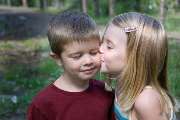 A little girl kissing a boy on the cheek.