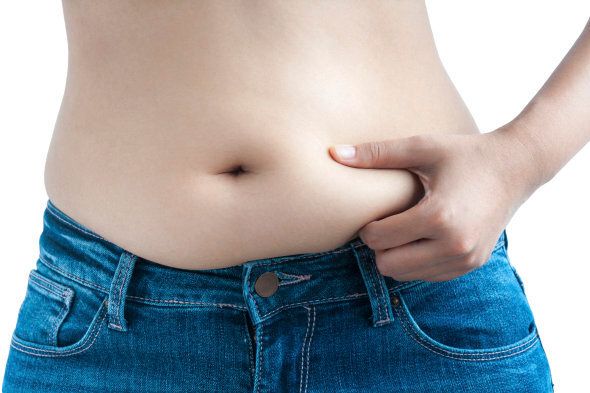 A Woman Wearing Blue Jeans Pinches Her Belly Fat