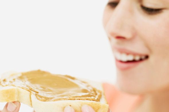 close-up of a teenage girl holding a slice of bread with peanut butter