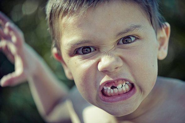 Portrait of boy with missing front tooth, looking threateningly into camera.