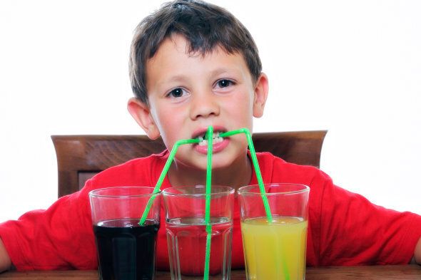 This is an image of a beautiful child drinking three different kind of sodas.
